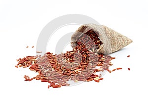 Pile of uncooked riceberry red rice small sack and wooden spoon