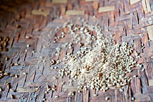 A pile of unpeeled and peeled rice in woven bowl