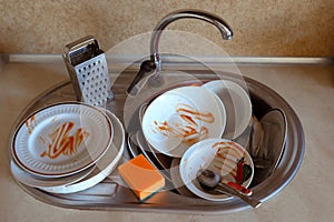 Pile of unwashed, dirty dishes in the sink. Mess in the kitchen. Dirty kitchenware, plates and mugs