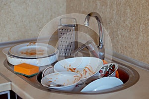 Pile of unwashed, dirty dishes in the sink. Mess in the kitchen. Dirty kitchenware, plates and mugs