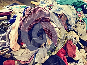 Pile of used clothes on sale in a flea market, filtered photo