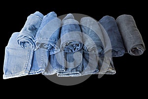 A pile of variety jeans were folded together show bottom of leg part lay  omn black background