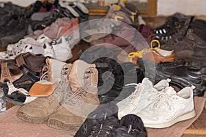 Pile of the various old worn footwear, selective focus