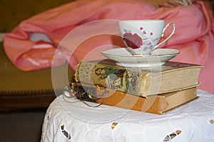 Pile of vintage books with a delicate vintage teacup and saucer on top