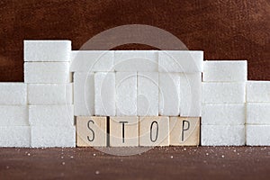 Pile or wall of sugar cubes and stop word in block letters as advise on addiction calories excess and sweet unhealthy food abuse