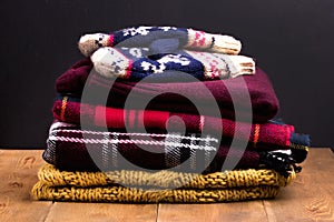 Pile of warm and cozy winter and autumn clothes on wooden background Sweaters cardigans scarf mittens