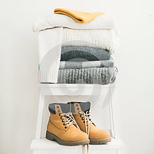 Pile of warm sweaters, blankets, cap and boots, square crop