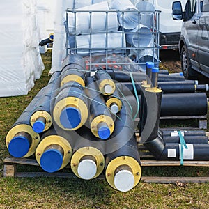 A pile of water pipes with thermal insulation on a construction site