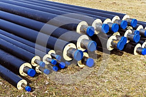 A pile of water pipes with thermal insulation in a meadow