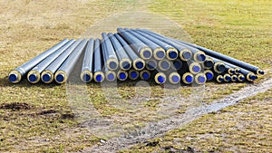 A pile of water pipes with thermal insulation in a meadow