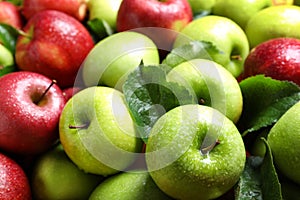 Pile of wet apples with leaves as background