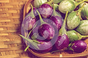 Pile of wet purple and green eggplant on bamboo wooden background