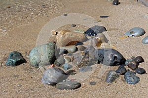 A pile of wet rocks on a sandy beachn at Point Loma, California