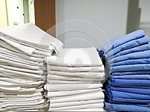 Pile of white and blue cloth, towel, bedspread, bedsheet in the hospital, with blur white background