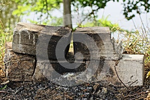 A pile of white burnt bricks in black soot on an old extinguished fire