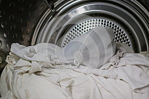 A pile of white clothing with laundry bag in a dryer.