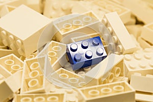 Pile of white color building blocks with selective focus and highlight on one particular blue block using available light