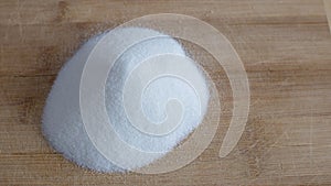 Pile of white granulated sugar on a wood cutting board