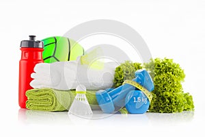 Pile of white and green towels with red bicycle water bottle and green rubber handball in the background with green lettuce, a pa