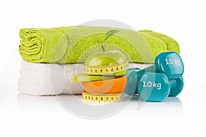 Pile of white and green towels with two blue vinyl coated dumbbells