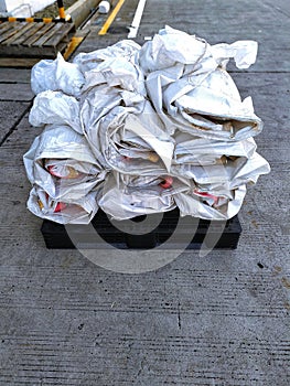 Pile of white paper bags tied and placed on a black wooden pallet