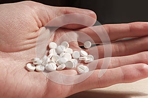Pile of white pills on the male hand