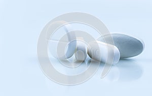 Pile of white round and oblong shape tablet pills on white background. Pharmaceutical industry. Pharmacy or drugstore photo