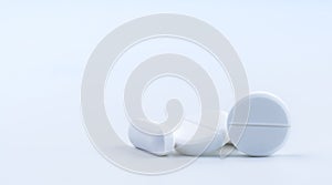 Pile of white round and oblong shape tablet pills on white background. Pharmaceutical industry. Pharmacy or drugstore