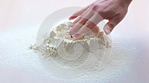 Pile of white wheat flour was poured on light table woman's hand bread pizza kneading dough with hands homemade