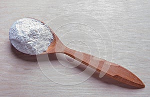 Pile of white wheat flour in wooden spoon