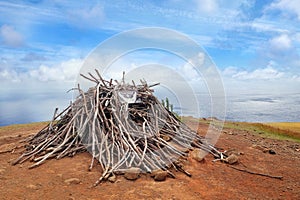 Pile of wood with a sign on the slopes of the Terevaka Volcano on Easter Island, against a blue sky.
