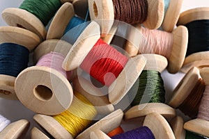 Pile of wooden spools with colorful sewing threads, closeup