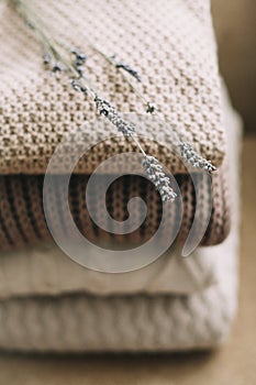 Pile of woolen plaids on a light background.  Stack of knitted clothes sweaters, scarves, pullovers.