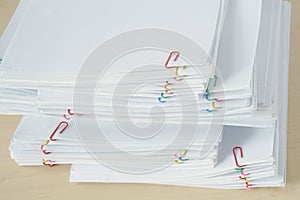 Pile of workload paperwork and reports with colorful paper clip