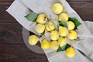 A pile of yellow pears scattered on a dark wooden table.