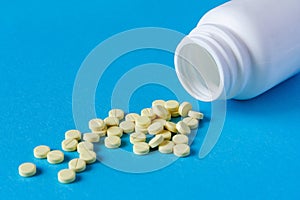 A pile of yellow tablets from a white plastic jar