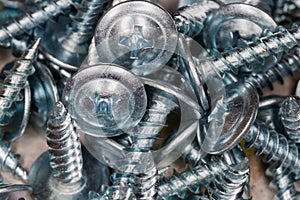 Pile of zinc plated cross recessed sheetmetal screws, close-up photo