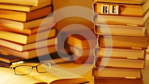 Piles of books on a table. Near the open book with glasses appears the inscription BESTSELLERS. Stop motion