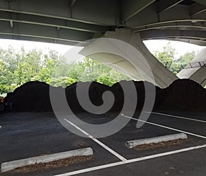 Piles of brown mulch under a bridge