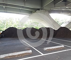 Piles of brown mulch under a bridge