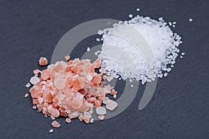 Piles of Coarse Sea Salt and Himalayan Pink Salt on dark