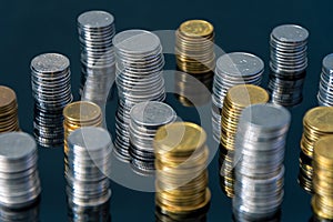 Piles of coins (polish zloty, grosze, PLN) on a black, reflective surface.