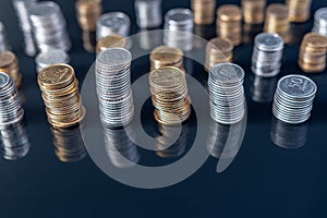 Piles of coins (polish zloty, grosze, PLN) on a black, reflective surface.