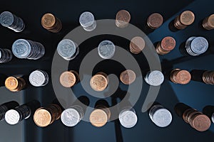 Piles of coins (polish zloty, grosze, PLN) on a black, reflective surface seen from the top.