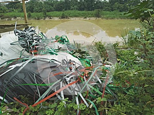 Piles of colorful plastic rope rubbish are scattered on the edge of a river