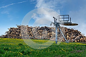 Piles of fir logs piled up with blue sky and green meadow. End of ski lift. Monte Avena  Belluno  Italy