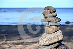 Piles of gray stones are stacked in a Zen pyramid on the Baltic Sea coast for close-up meditation.