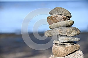 Piles of gray stones are stacked in a Zen pyramid on the Baltic Sea coast for close-up meditation.
