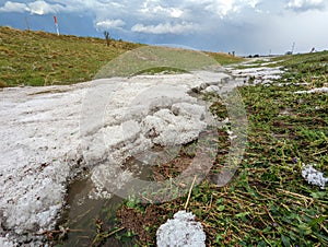 Piles of hail several inches deep fill the ditch along a highway after a storm.