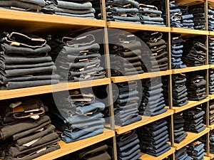Piles of modern jeans of different sizes. A selection of jeans in a clothing store. Shelves with clothes in the department of